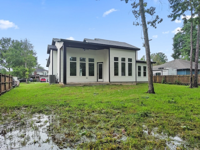 back of house featuring central air condition unit and a lawn