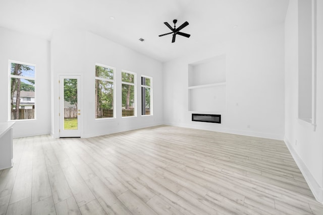 unfurnished living room featuring ceiling fan, built in features, and light hardwood / wood-style flooring