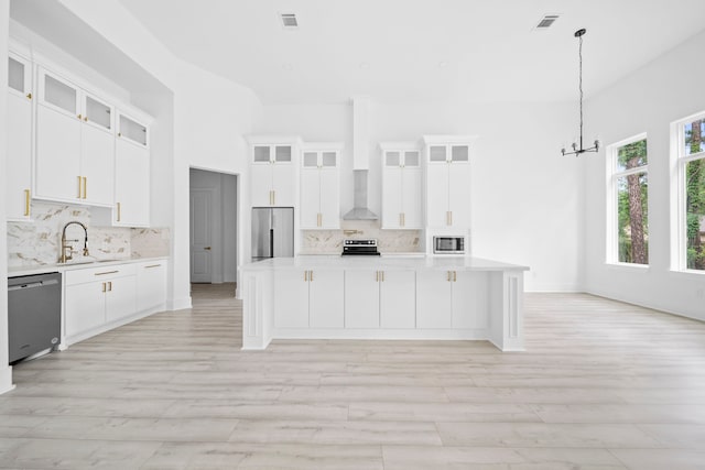 kitchen featuring a center island, white cabinets, stainless steel appliances, and decorative light fixtures