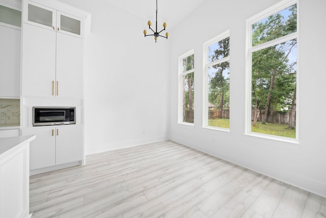 unfurnished dining area featuring light hardwood / wood-style floors and an inviting chandelier