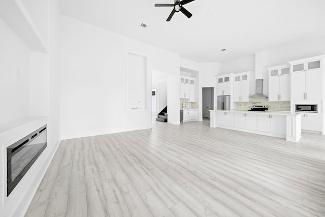 unfurnished living room featuring ceiling fan, sink, and light hardwood / wood-style flooring