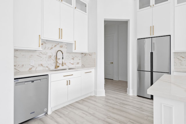 kitchen with sink, light hardwood / wood-style flooring, decorative backsplash, white cabinetry, and stainless steel appliances