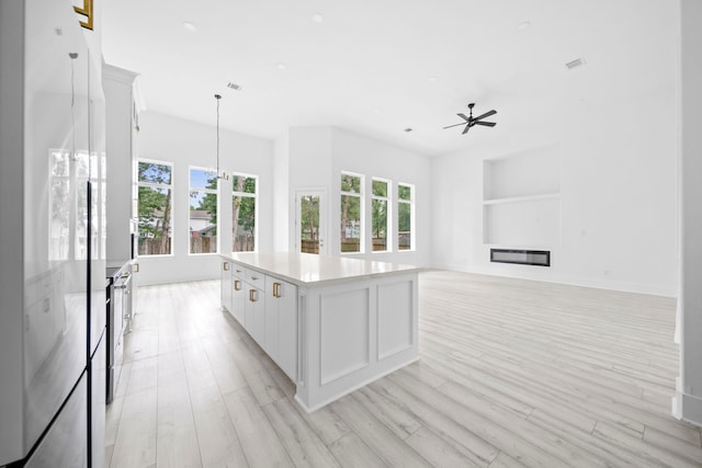 kitchen featuring pendant lighting, a kitchen island, white cabinetry, and light hardwood / wood-style floors