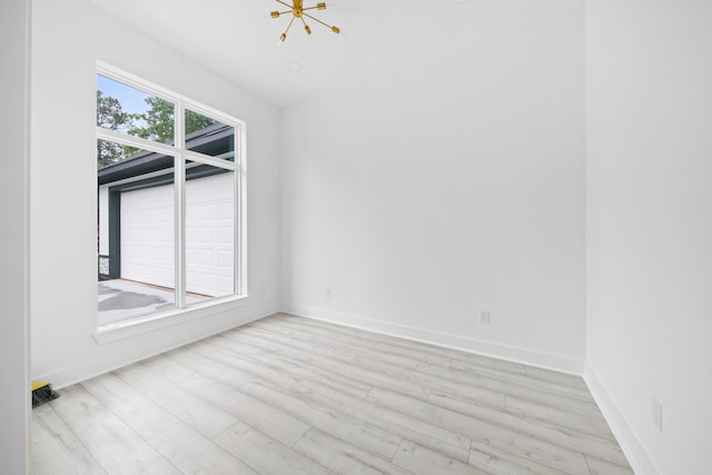 spare room with light wood-type flooring and a notable chandelier