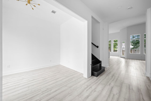 unfurnished living room with a notable chandelier and light hardwood / wood-style flooring