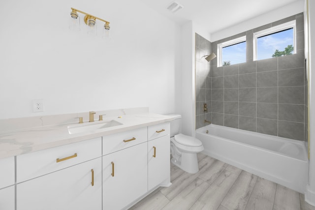 full bathroom featuring hardwood / wood-style floors, vanity, toilet, and tiled shower / bath