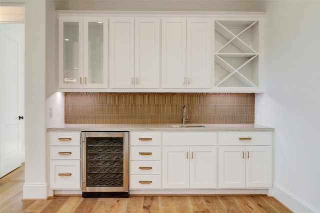 bar with decorative backsplash, white cabinetry, sink, and wine cooler