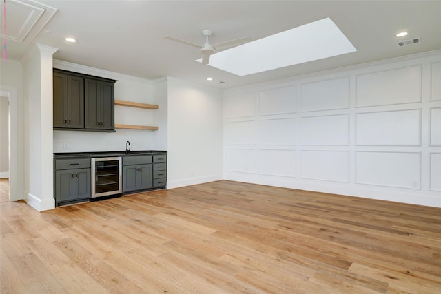 bar featuring light wood-type flooring, ornamental molding, and wine cooler