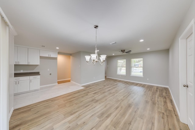 unfurnished dining area featuring light hardwood / wood-style floors and ceiling fan with notable chandelier