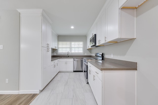 kitchen featuring appliances with stainless steel finishes, light hardwood / wood-style flooring, white cabinetry, and sink