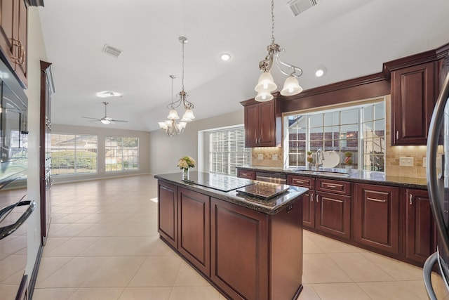 kitchen with tasteful backsplash, ceiling fan with notable chandelier, sink, decorative light fixtures, and a center island