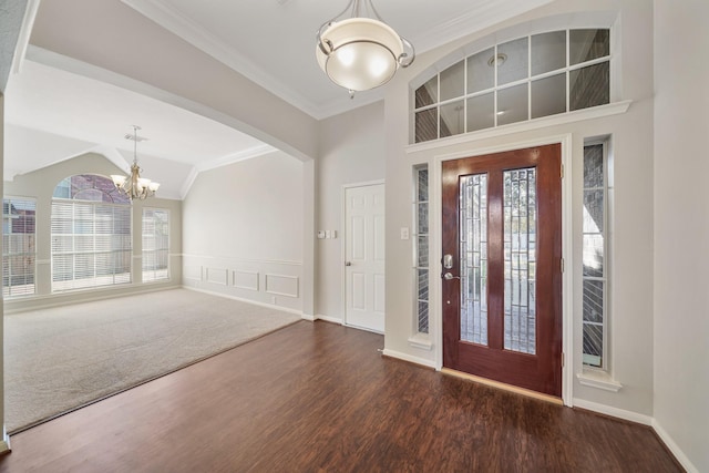 foyer entrance with dark hardwood / wood-style flooring, a chandelier, lofted ceiling, and ornamental molding