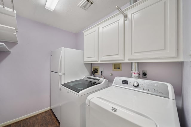 washroom with dark wood-type flooring, washer and clothes dryer, cabinets, and a textured ceiling