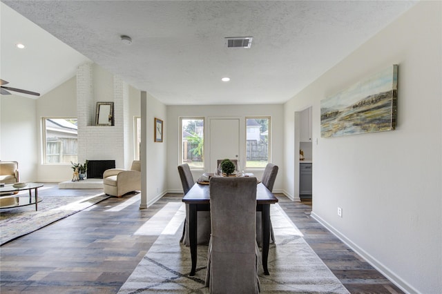 dining space with dark hardwood / wood-style floors, ceiling fan, lofted ceiling, and a fireplace