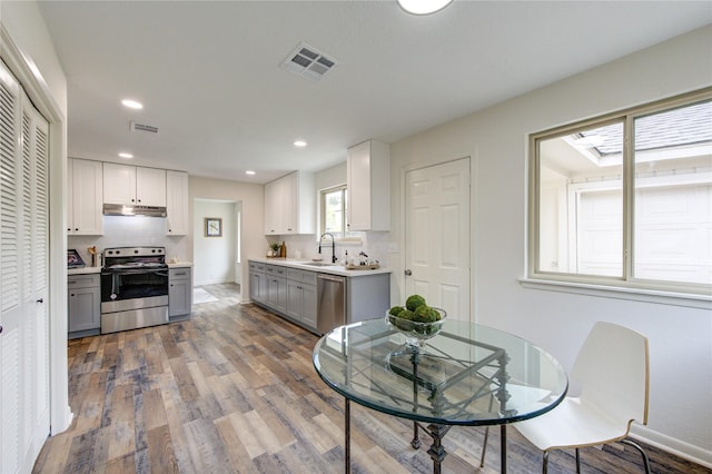 kitchen featuring gray cabinetry, stainless steel appliances, sink, white cabinets, and light hardwood / wood-style floors