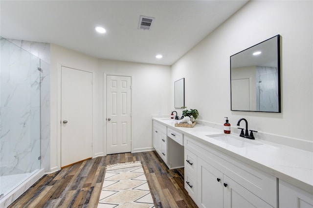 bathroom with hardwood / wood-style floors, vanity, and a shower with shower door