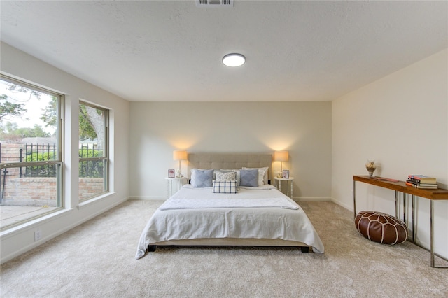 bedroom featuring light carpet and a textured ceiling