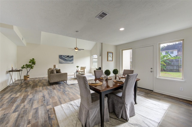 dining room with ceiling fan, wood-type flooring, a textured ceiling, and vaulted ceiling