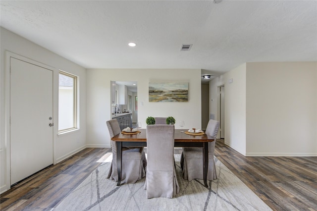 dining room with sink, dark hardwood / wood-style flooring, and a textured ceiling