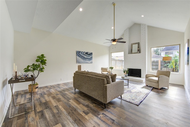 living room with ceiling fan, dark hardwood / wood-style flooring, high vaulted ceiling, and a brick fireplace