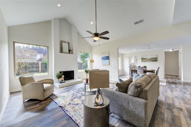 living room with hardwood / wood-style flooring, ceiling fan, high vaulted ceiling, and a brick fireplace