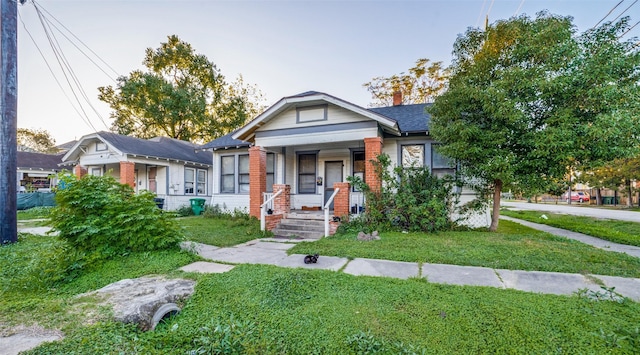 bungalow-style house featuring a front yard and covered porch