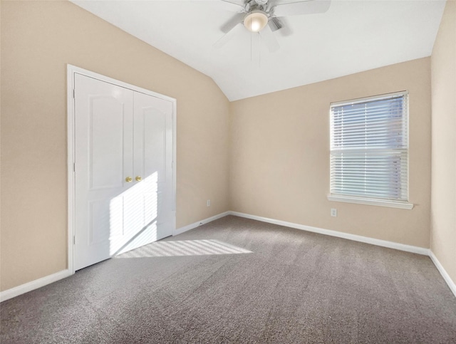 carpeted spare room with ceiling fan and vaulted ceiling