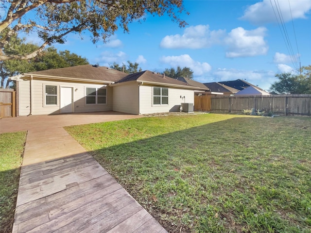 rear view of property with a yard, cooling unit, and a patio