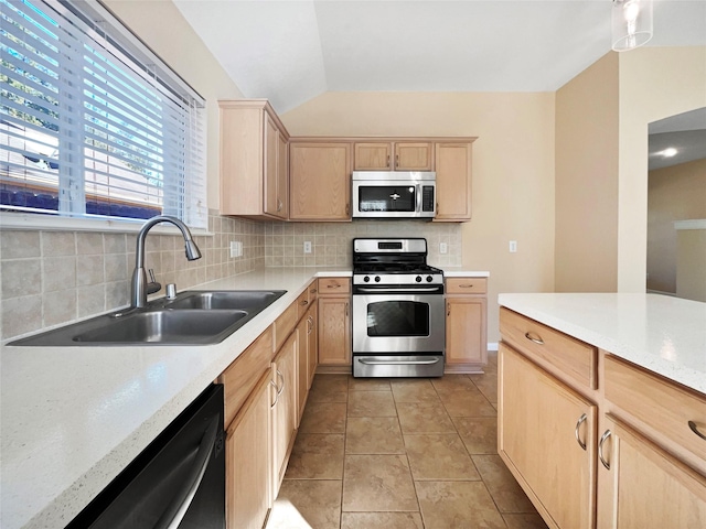 kitchen featuring lofted ceiling, sink, decorative backsplash, light brown cabinetry, and appliances with stainless steel finishes