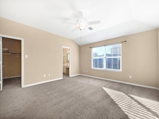 unfurnished bedroom featuring a walk in closet, ensuite bathroom, ceiling fan, a closet, and lofted ceiling