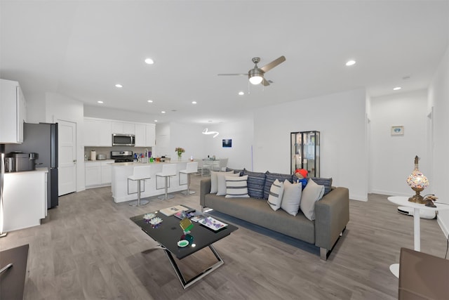 living room with ceiling fan and light hardwood / wood-style flooring