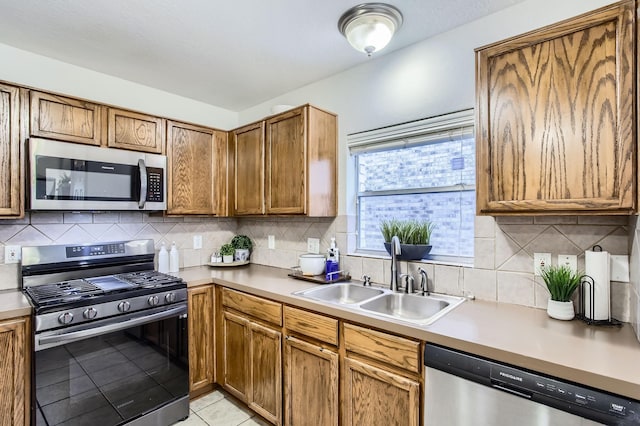 kitchen with tasteful backsplash, sink, light tile patterned floors, and appliances with stainless steel finishes