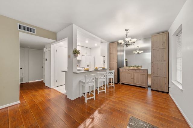 kitchen featuring dark hardwood / wood-style floors, light brown cabinets, white refrigerator with ice dispenser, and a chandelier