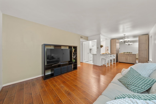 living room with an inviting chandelier and light hardwood / wood-style flooring