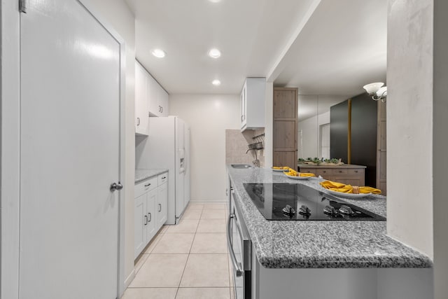 kitchen with white refrigerator with ice dispenser, white cabinets, light stone countertops, black electric cooktop, and light tile patterned floors