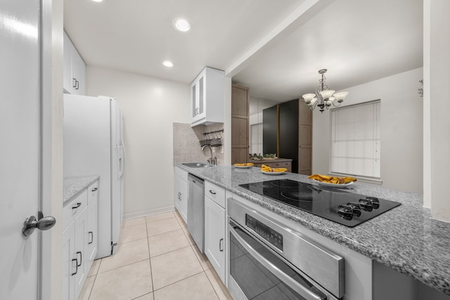 kitchen with light stone countertops, appliances with stainless steel finishes, sink, an inviting chandelier, and white cabinets