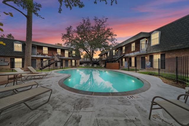 pool at dusk featuring a patio