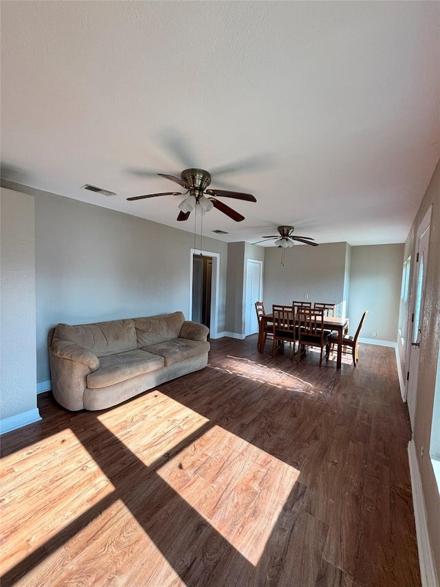 living room with ceiling fan and dark wood-type flooring