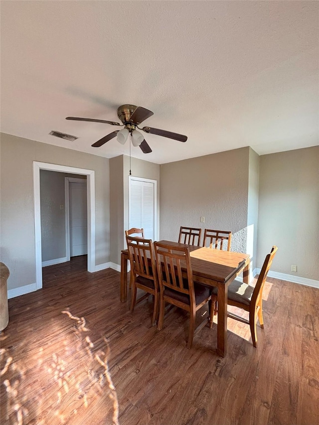 dining space with a textured ceiling, ceiling fan, and dark wood-type flooring