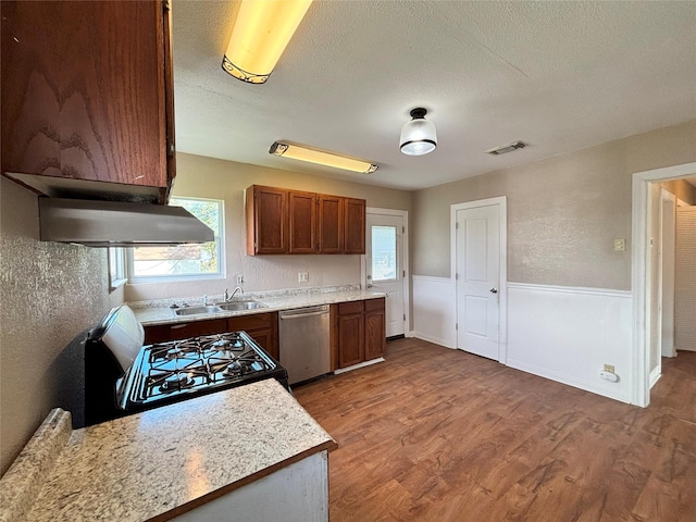 kitchen featuring sink, stainless steel dishwasher, stove, a textured ceiling, and hardwood / wood-style flooring