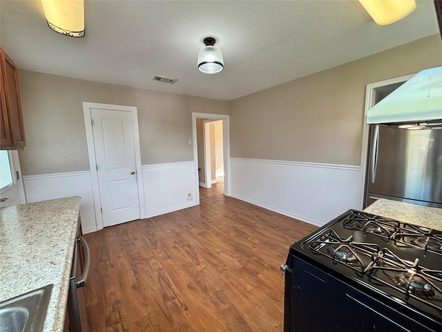 kitchen with sink, stainless steel fridge, gas stove, and hardwood / wood-style floors