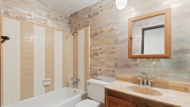 full bathroom featuring vanity, tiled shower / bath combo, and toilet