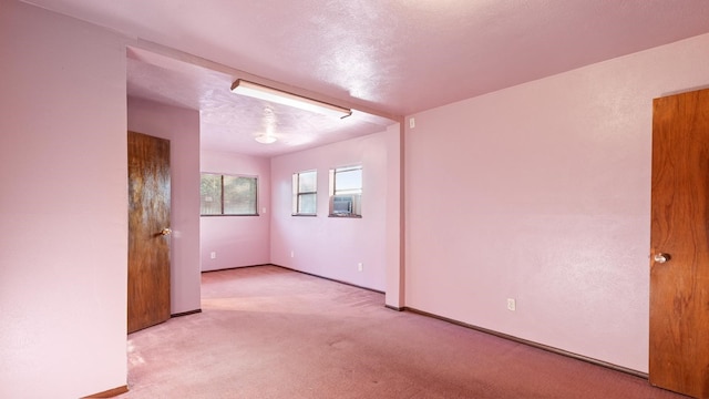 empty room with a textured ceiling, light colored carpet, and cooling unit