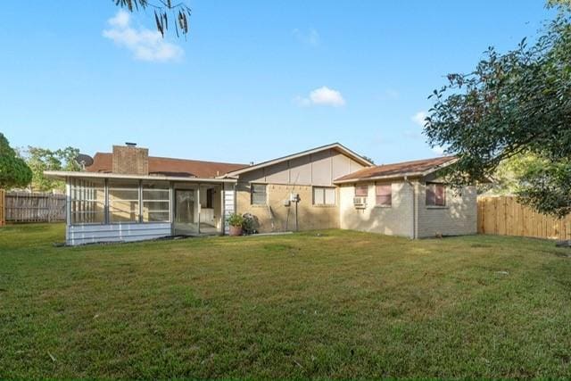 rear view of property with a sunroom and a yard