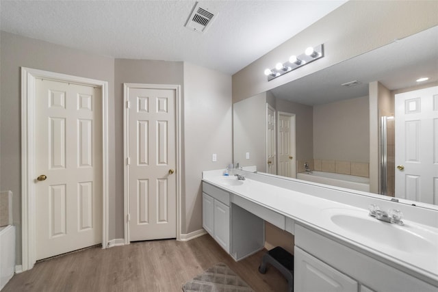 bathroom featuring a bathing tub, vanity, wood-type flooring, and a textured ceiling