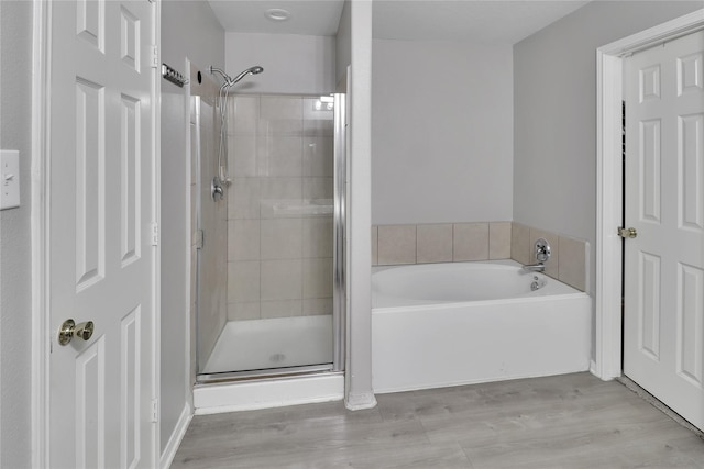 bathroom featuring plus walk in shower and hardwood / wood-style flooring