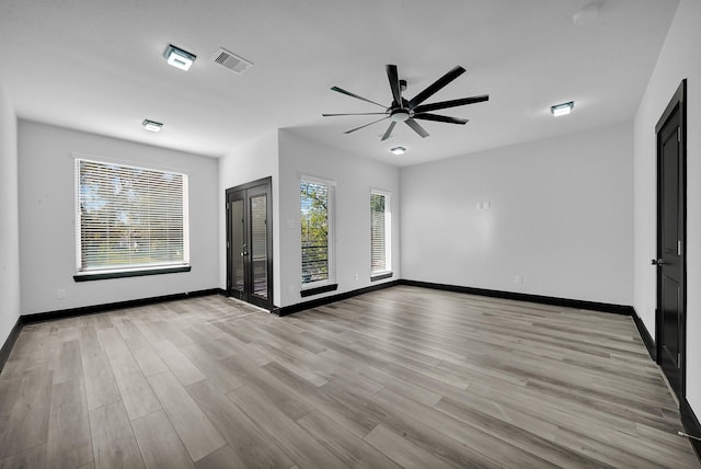 spare room featuring light wood-type flooring, a wealth of natural light, and ceiling fan