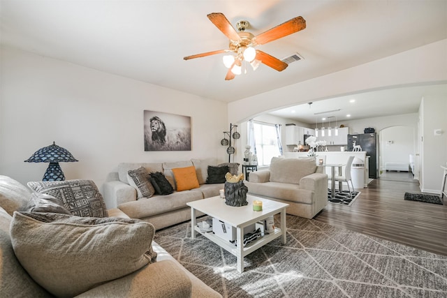 living room featuring ceiling fan and dark hardwood / wood-style floors