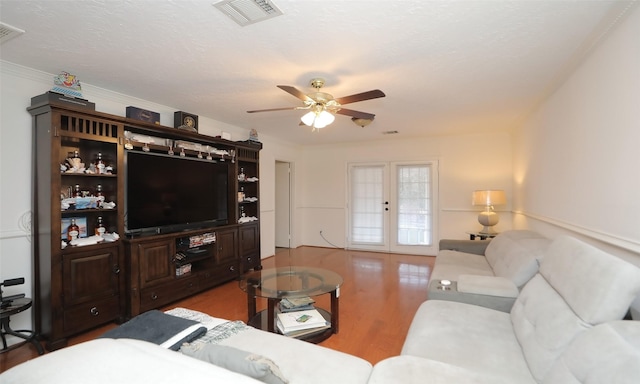 living room featuring french doors, ornamental molding, a textured ceiling, ceiling fan, and hardwood / wood-style floors