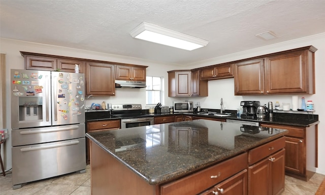 kitchen with a center island, sink, stainless steel appliances, a textured ceiling, and ornamental molding